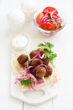 Kuzu kebap şişleri soğan ve ayran soslu üzerinde.