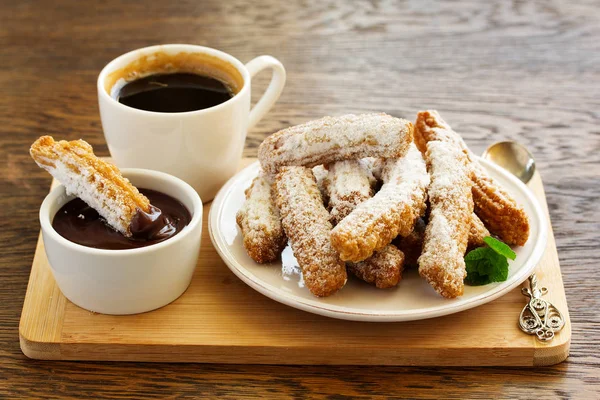 Churros with hot chocolate and powdered sugar.