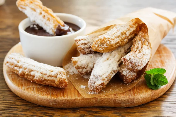 Churros with hot chocolate and powdered sugar.