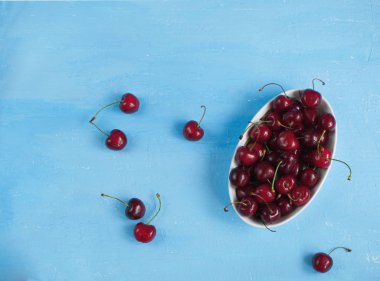 Ummer çilek hasat kavramı, beyaz porselen kase taze kiraz natürmort, açık mavi renkli, kopya alanı üzerinde üstten görünüm