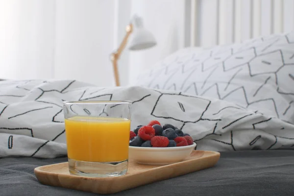 Breakfast bed Wooden tray Hotel room Early morning Concept interior Copy space Geometric sheet and pillow case Berries Orange juice