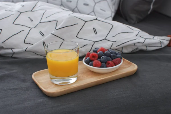 Breakfast bed Wooden tray Hotel room Early morning Concept interior Copy space Geometric sheet and pillow case Berries Orange juice