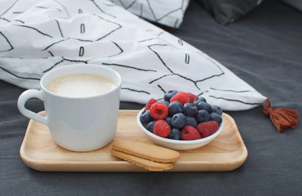 Breakfast bed Wooden tray Hotel room Early morning Concept interior Copy space Geometric sheet and pillow case Berries Cappuccino cup Biscuits