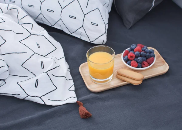Breakfast bed Wooden tray Hotel room Early morning Concept interior Copy space Geometric sheet and pillow case Berries Orange juice Biscuits