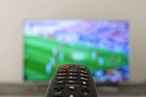 Whatching football concept Remote controll with blured tv on th background