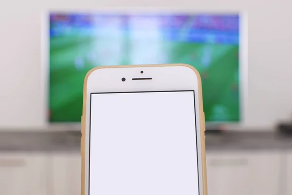 Futbol fan paylaşım oyun sonuç kavram Smartphone ile arka plan kumar kavramı üzerinde televizyonda futbol maç ile boş beyaz ekran