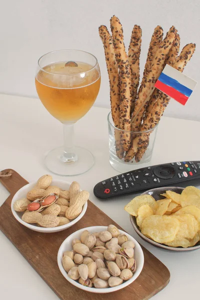 Football snacks with russian flag flat lay Supporting national team concept Ready to watch football game Mundial Football fan food Beer, peanuts, pistacios, potato chips and tv remote control