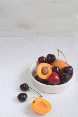 Kayısı ve beyaz porselen kiraz yaz sebze ve meyveleri kavramı hasat organik meyve beyaz arka plan kopya alanı kase