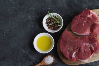 Taze çiğ et sığır eti biftek zeytinyağı baharat sıcak tuz tahta kaşık Biberiye Biber yemek kavramı yemek kavramı koyu beton arka üst düz koymak kopya alanı göster