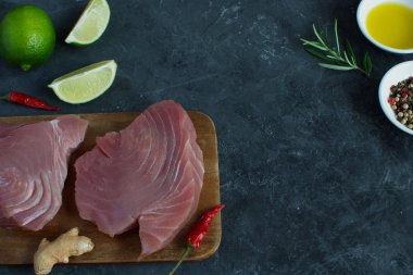 Ham orkinos biftek ahşap cutboard kireç dilim zeytin yağı Rosemary Fresh zencefil kökü Chili biber karışımı siyah beton arka plan kopya alanı üstten görünüm yemek madde Asya gıda düz düşük anahtar yatıyordu