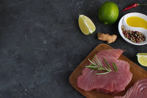 Ham orkinos biftek ahşap cutboard kireç dilim zeytin yağı Rosemary Fresh zencefil kökü Chili biber karışımı siyah beton arka plan kopya alanı üstten görünüm yemek madde Asya gıda düz düşük anahtar yatıyordu