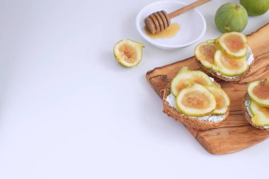 Taze taze incir ahşap cutboard bütün tahıl ekmeği tatlım keçi peyniri sağlıklı beslenme kavramı kanepeler sandviç meze kopya beyaz arka plan boşluk