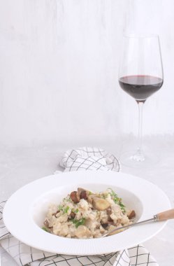 Mantarlı risotto geleneksel İtalyan porcino pirinç kırmızı şarap cam tabak beyaz arka plan Checkered peçete kopya alanı