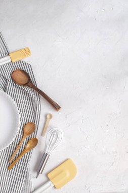 Mutfak eşyaları pişirme kavramı - beyaz seramik tart için pan, çırpma teli, tahta kaşıklar, silikon spatula, buruşuk çizgili peçete üzerinde fırça kötek. Üstten görünüm, düz lay, kopya alanı.