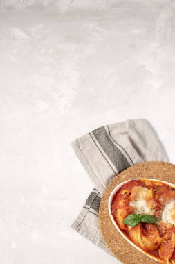 İtalyan mutfağı düz yatıyordu mockup - fırında makarna ile domates ve mozzarella peyniri sosu, fesleğen yaprağı, beyaz arka plan, kopya alanı üzerinde rustik peçete.