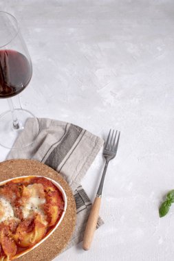 İtalyan mutfağı düz yatıyordu mockup - domates ve mozzarella peyniri sosu, fesleğen yaprağı, kırmızı şarap cam, beyaz arka plan, kopya alanı üzerinde rustik peçete ile makarna pişmiş.