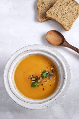 Ekmek ve tahta kaşık ile en az bir resim - kabak çorbası plaka. Üstten görünüm, gri arka plan, kopya alanı.