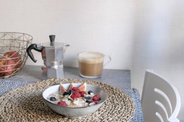 Sağlıklı kahvaltı masası - olgun organik ahududu, yaban mersini ve incir, kapuçino, moka kahve makinesi ile yulaf lapası kase.