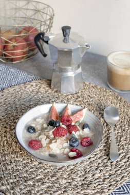 Sağlıklı kahvaltı masası - olgun organik ahududu, yaban mersini ve incir, kapuçino, moka kahve makinesi ile yulaf lapası kase.