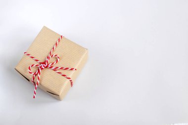 Noel ve yeni yıl kavramı - Kraft kağıt bükülmüş kırmızı ve beyaz kordon ile mevcut kutusunda. Beyaz arka plan, üstten görünüm, kopya alanı.