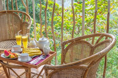 Güzel teras ya da balkon, Otel Oda Kahvaltı, çare - taze karpuz, mango, muz, güler yüzlü, krep, Çaydanlık, bardak, rattan koltuk