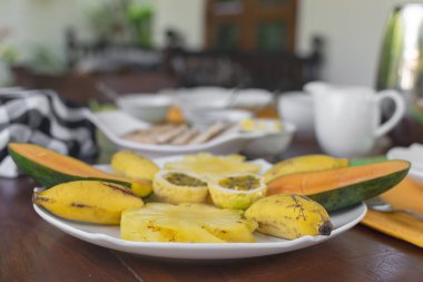 Güzel kahvaltı - seçici odak taze tutku meyve, mango, muz, ananas, Çaydanlık, bardak ve arka plan üzerinde servis
