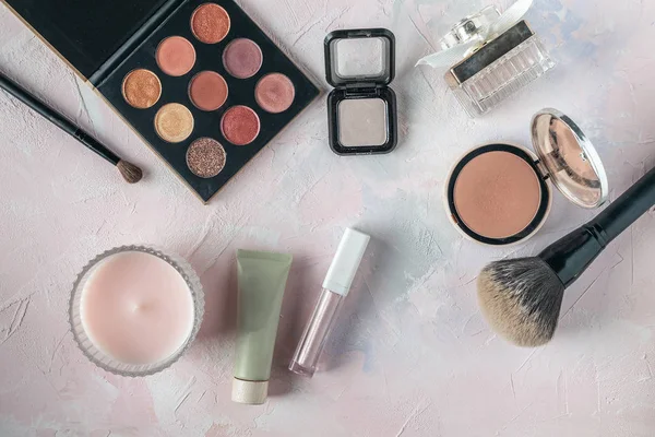 Makeup products, beauty, blogger, social media, magazines flat lay - powder, eyeshadows, perfume, makeup brush on pastel pink background, copy space