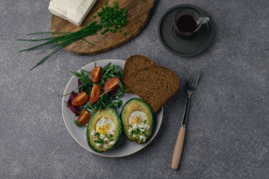 Sağlıklı Kahvaltı, beslenme - pişmiş avokado, roka, domates, kepekli ekmek yanında beyaz peynir, ahşap kesme tahtası, espresso kahve üzerinde chives