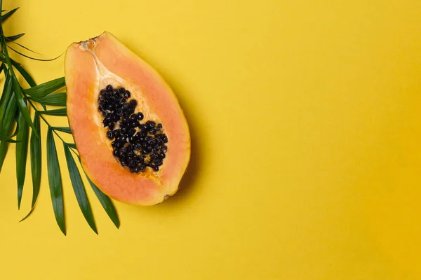 Mevsimlik tropikal meyve, yerel pazar yarım taze olgun papaya, palmiye ağacı yaprağına sarı arka plan, üstten görünüm, düz lay, alanı Kopyala