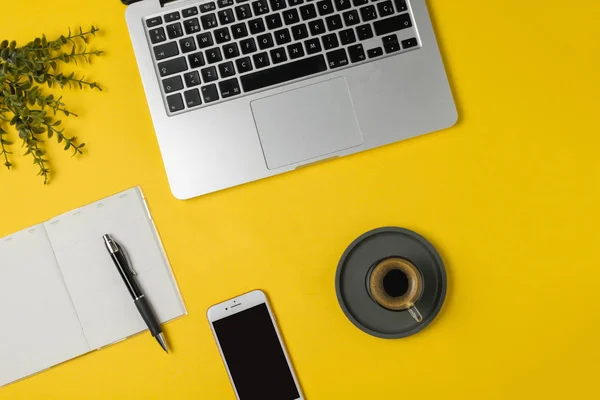 Çalışma alanı serbest meslek, blogger, gazeteci - dizüstü bilgisayar, Not defteri, kalem, kahve Kupası, parlak sarı arka plan, üstten görünüm, düz lay, smartphone kopyalama alanı