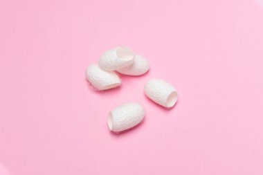 Beyaz ipekböceği kabuk pembe arka plan - spa cilt bakım kavramı, kaynak ipek kumaş ve İpek iplik üzerinde koza