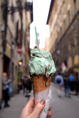 Geleneksel İtalyan gelato dondurma waffle koni yakın kadın elinde kadar arka planda, İtalyan şehir streen ile seyahat yaşam tarzı