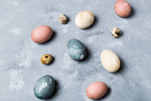 Spring easter minimal background - organic naturally dyed easter eggs, qual eggs, curcuma, beetroot, hibiscus tea pigments, gray background, rustic style, copy space, flat lay