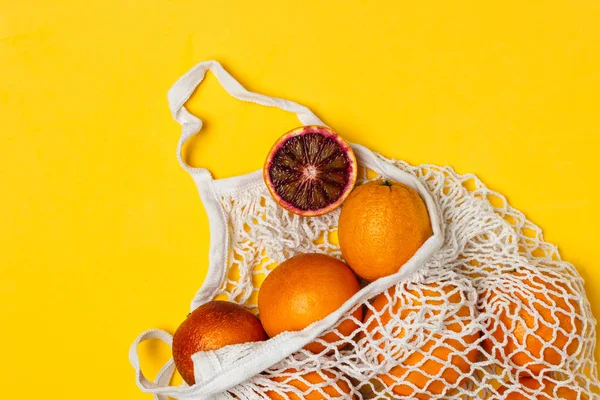 Naranjas sangrientas orgánicas en bolsa reutilizable de malla de algodón, respaldo amarillo — Foto de Stock