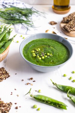 Beyaz ahşap masa üzerinde gri yay yeşil bezelye vejetaryen çorbası, se