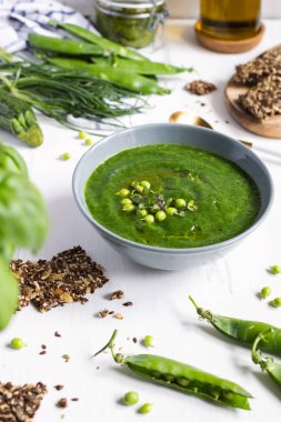 Beyaz ahşap masa üzerinde gri yay yeşil bezelye vejetaryen çorbası, se