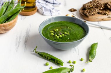 Beyaz ahşap masa üzerinde gri yay yeşil bezelye vejetaryen çorbası, se