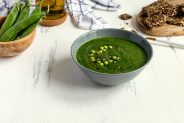 Beyaz ahşap masa üzerinde gri yay yeşil bezelye vejetaryen çorbası, se