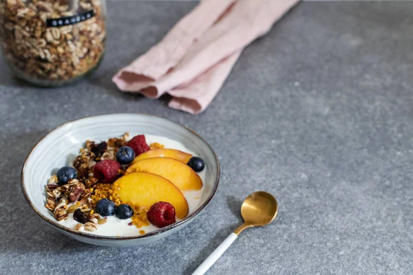 Гранола зі свіжим персиком йогурту, чорницею, малиною на табуреті — стокове фото