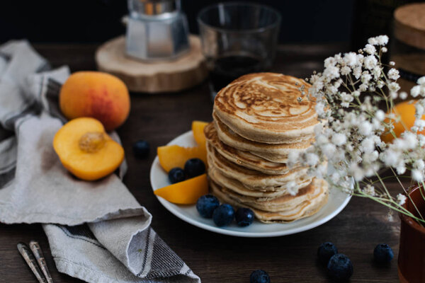 Beautiful rustic breakfast - pancakes with blueberries, peach, G