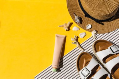 Hasır şapka, sandalet, parlak sarı arka plan üzerinde deniz kabukları, kopya