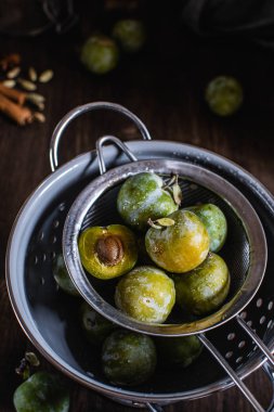 Koyu ahşap arka plan üzerinde gri kevgir yeşil erik