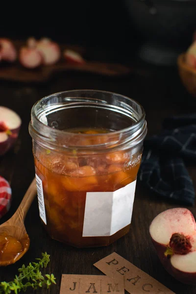 Conserve fatte in casa, marmellata di pesche con timo in vaso di vetro, legno scuro — Foto Stock