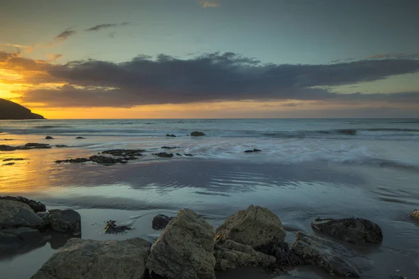 ウェールズ イギリスの美しいビーチでカメラまでやってくる潮の夕日 — ストック写真