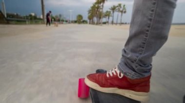 Erkek ayakları yere yakın barcelona plaj boyunca hareketli bir elektrikli kaykay üzerinde