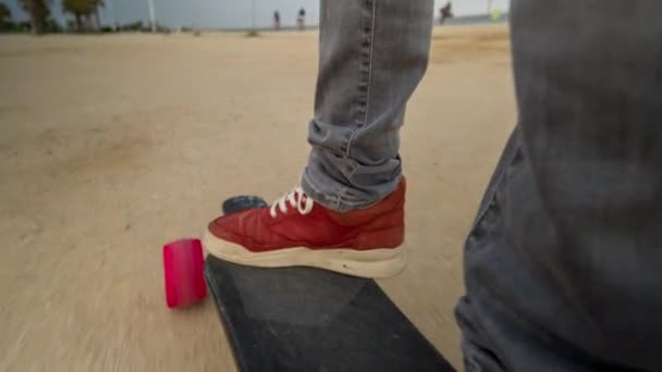 バルセロナのビーチ近くの地面に沿って移動電気スケート ボードの男性の足 — ストック動画