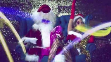 Güzel bayan Noel Baba 'yla disko Noel Baba' sı Noel süsleriyle ve süslü kulüpteki mavi deri koltukta takılarla eğleniyor. 