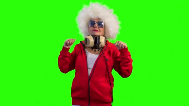 跳舞的老妇女与耳机在绿色背景 — 图库视频影像
