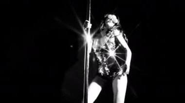 Şaşırtıcı direk dansör parlak kostüm siyah arka plan üzerine taşıma