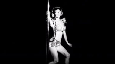 Şaşırtıcı direk dansör parlak kostüm siyah arka plan üzerine taşıma